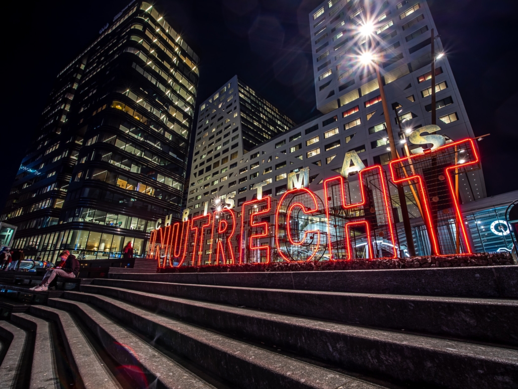 Utrechtse skyline 's nachts met verlichte letters en moderne gebouwen, perfect voor wie op zoek is naar een droomhuis met hulp van een makelaar in de stad