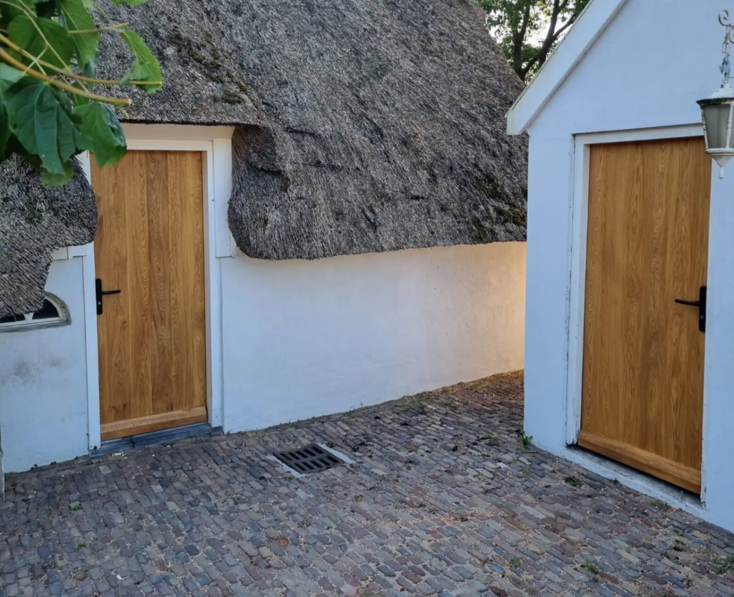 Traditioneel huis met houten voordeur en uitstekende isolatie, omgeven door een met riet bedekt dak en een geplaveide oprit.